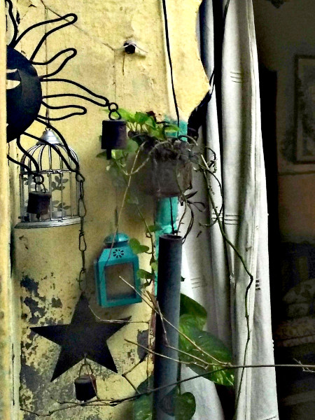 Potted plants and creepers soften the wrought iron of the wind chime while a bird cage and a lantern add whimsy.
